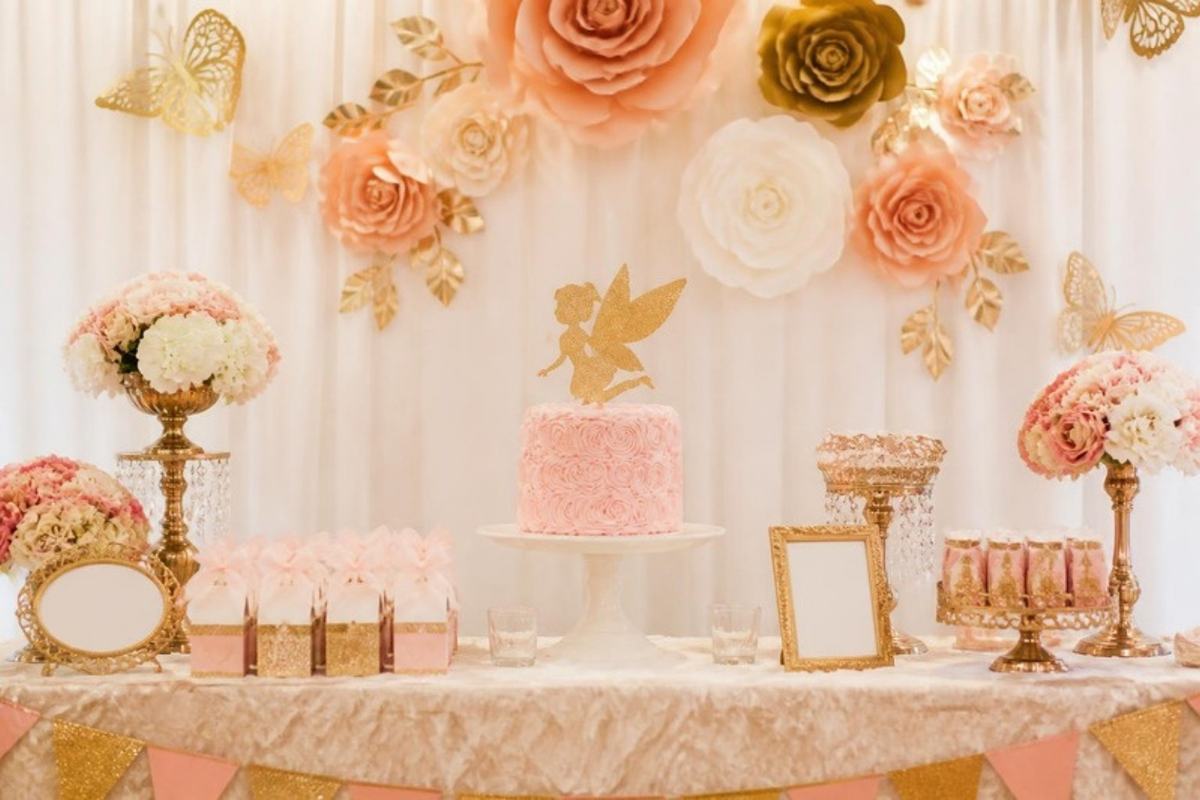 Mesa de postres con topper, flores de papel y cajitas para recuerdos
